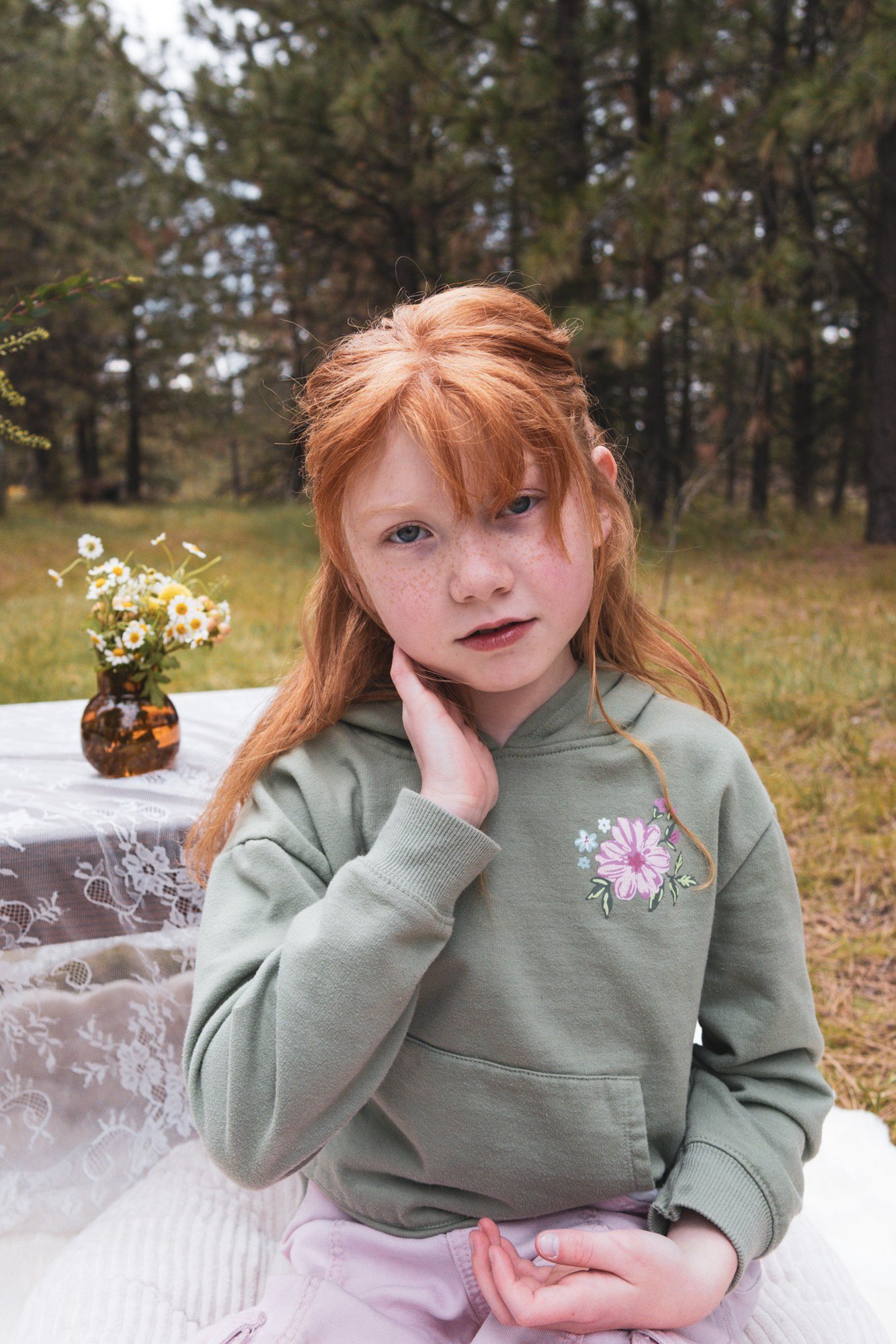 Outdoor portrait of a child beside a table of flowers