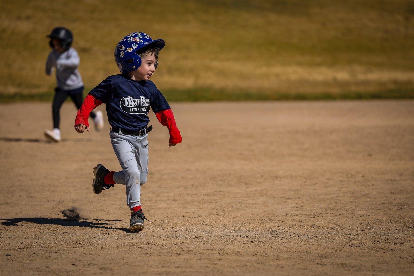 A young baseball player running across the field